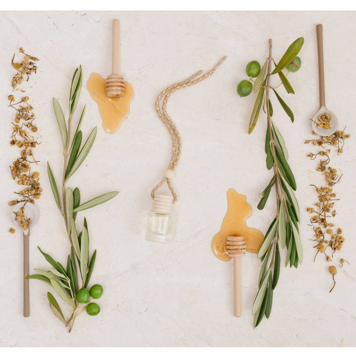 White tea car diffuser displayed with fresh herbs, honey, and botanicals in a styled flat lay arrangement
