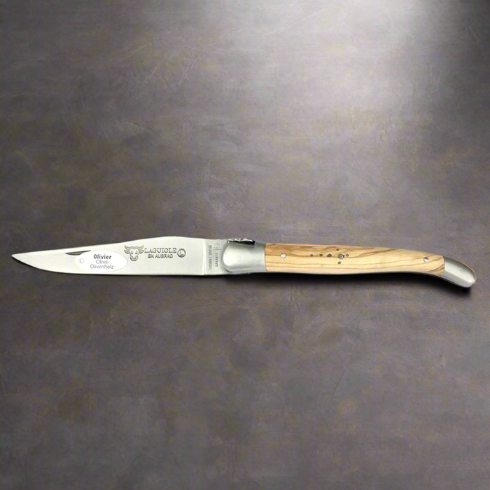 Open olive wood folding knife lying on a dark grey surface