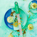 Microplane grater on a plate with green cupcakes and pistachios