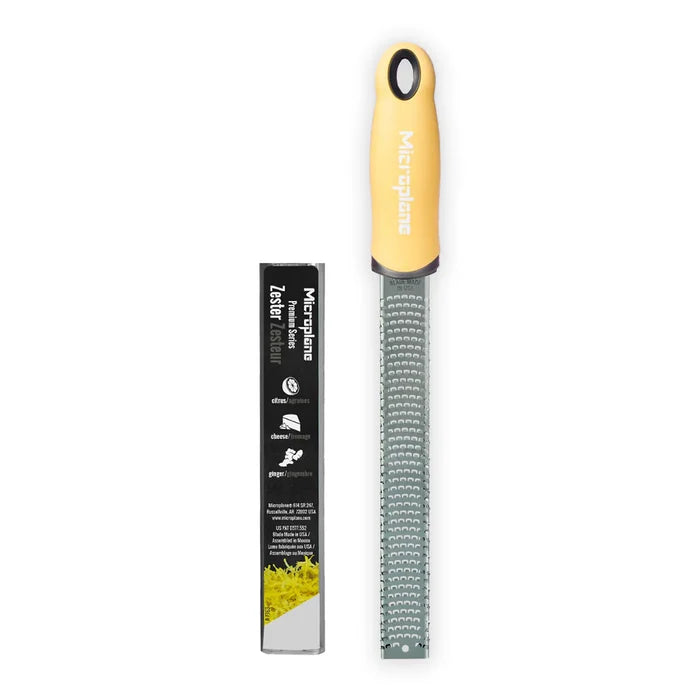 Zester with yellow handle and black label on a white background