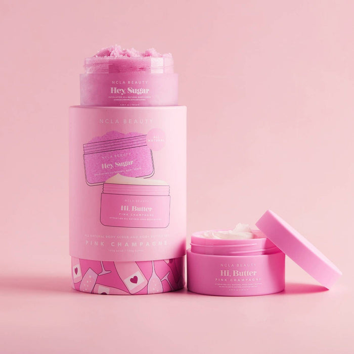 NCLA Beauty Pink Champagne body scrub and butter set with open jars on pink background