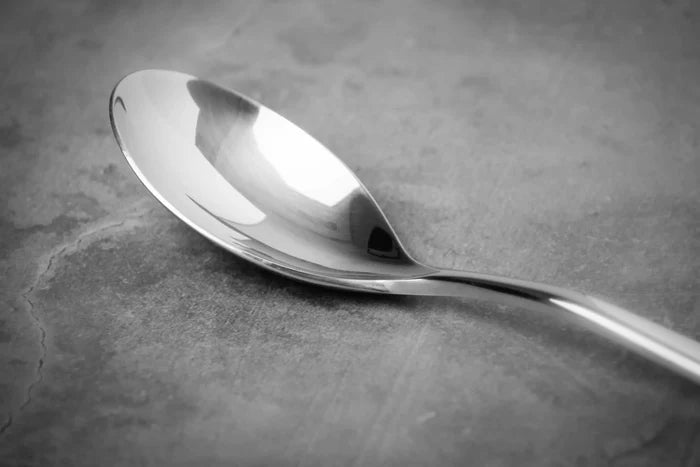 Closeup of Silver Titanium spoon on a gray surface.