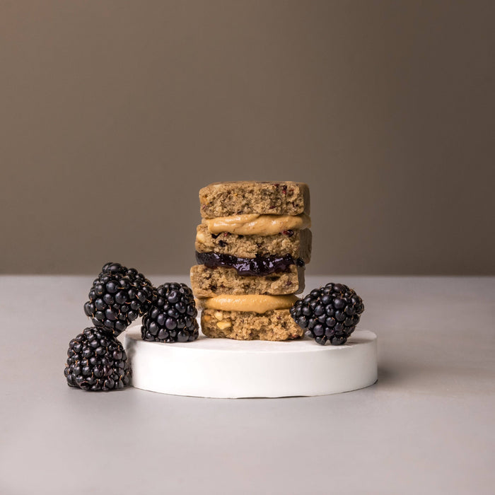Stack of peanut butter blackberry cookies with fresh blackberries on white platform